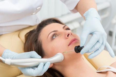 Cosmetic injection to the pretty caucasian woman face and beautician hands with syringe
